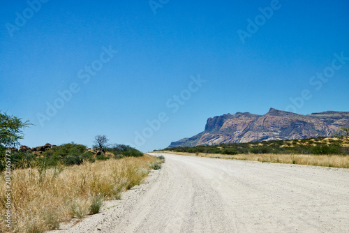 Bild auf Leinwand Schotterstraße vor Berglandschaft bei Bulls Party nahe der Spitzkoppe