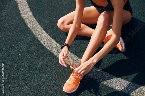 Fit woman tying up laces on her sport shoes