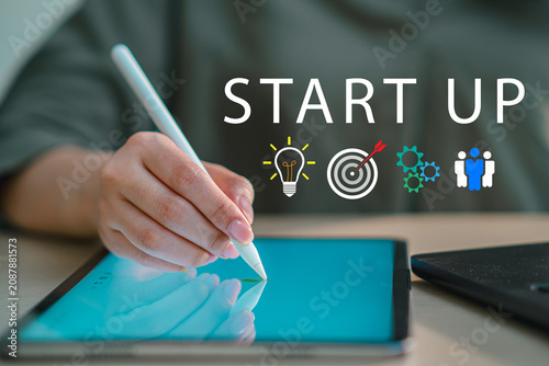 Businessperson using digital tablet with Start Up text graphics and strategic icons