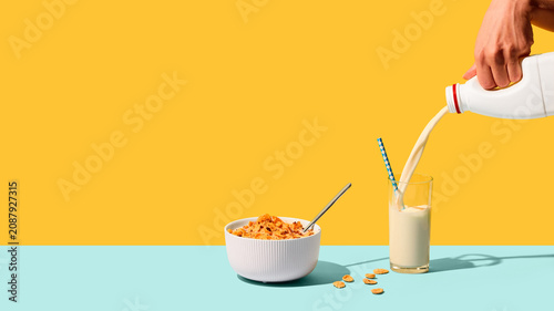 Foto Milk poured into glass beside breakfast cereal on colorful studio background