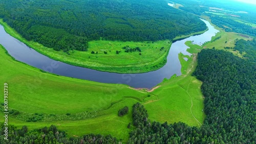 Aerial landscape featuring winding river, lush green fields, and dense forest seen from above