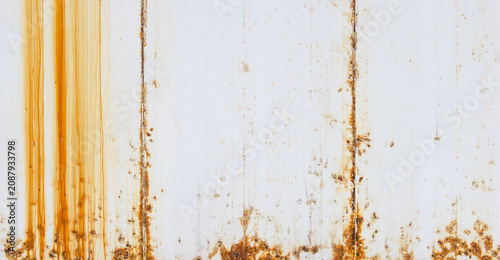 A high-resolution texture of a white painted full frame metal surface with heavy orange rust streaks and weathered grunge details on it, perfect for industrial backgrounds. Background Pattern.