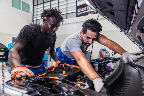 Tableau sur toile Professional EV technicians collaborating to diagnose and resolve an electrical problem in a modern electric vehicle service workshop