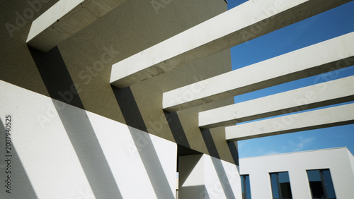 Modern architectural concrete beams casting geometric shadows on a building facade under blue sky