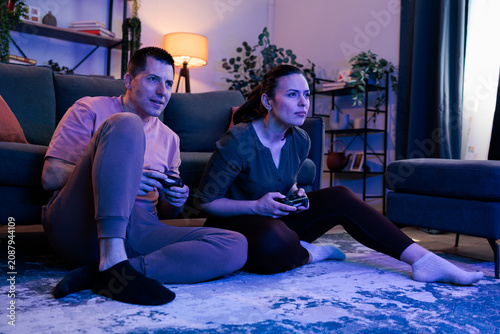 Photography Young couple playing video games at home at night