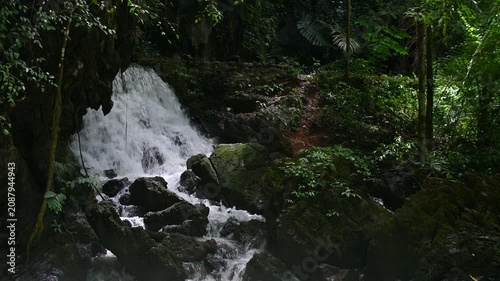 Beautiful waterfall flowing through lush green rainforest and mossy rocks, natural tropical jungle landscape background. Tao Thong Waterfall, Phang Nga Province, Thailand.
