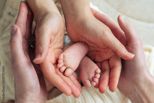 Parents holding newborn baby feet together