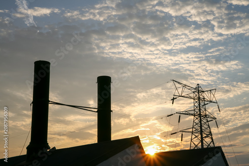 Photos Industrial chimneys and electricity pylon silhouetted against a bright sunset sk
