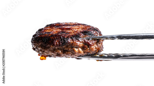 Juicy burger patty held in tongs, dripping with grilled fat, sizzling on white backdrop