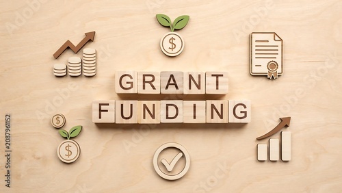 Grant funding text written on wooden blocks surrounded by financial growth icons on light wood background
