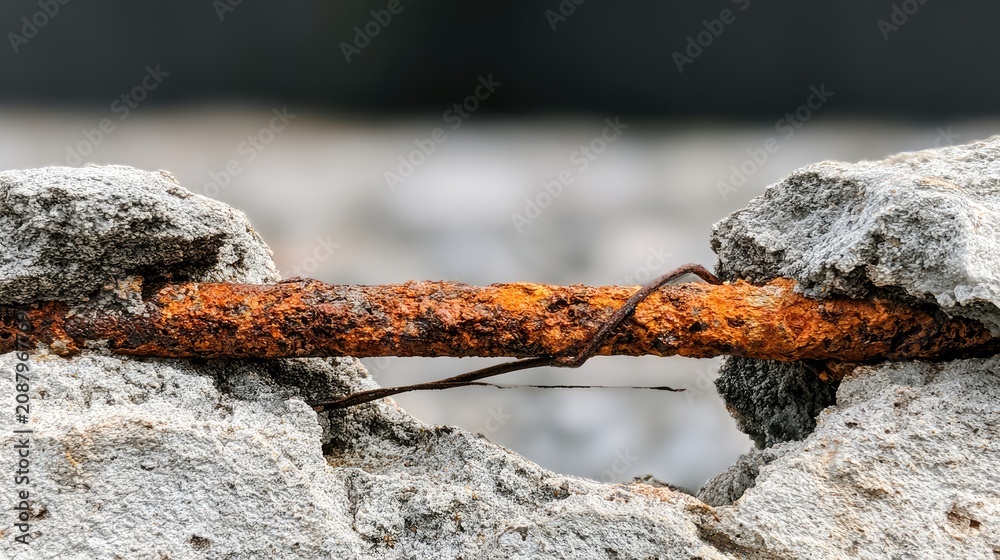 Fototapeta premium Close-up of corroded rebar protruding from weathered concrete
