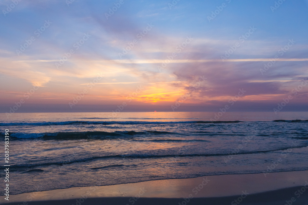 Obraz premium A serene, wide-angle seascape, captures gentle waves lapping onto a sandy shore