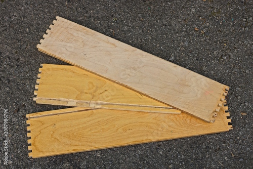 A set of brown gray wooden rectangular planks of furniture boards with grooves lie on the gray asphalt on a daytime street