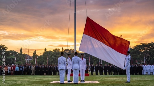 Honor guard raising the Indonesian flag during an Independence Day ceremony at sunrise with dramatic skies, ceremonial formation, patriotic spirit, and realistic documentary style.