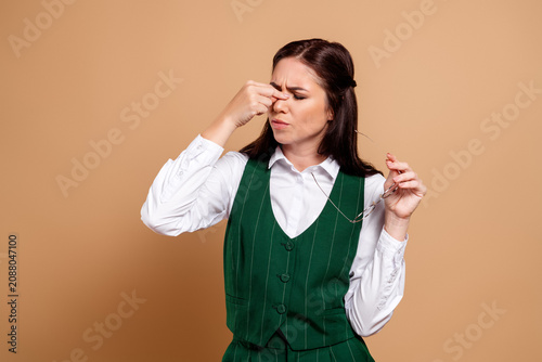 Photography Business woman pinching her nose in disgust while holding glasses, tired and fru