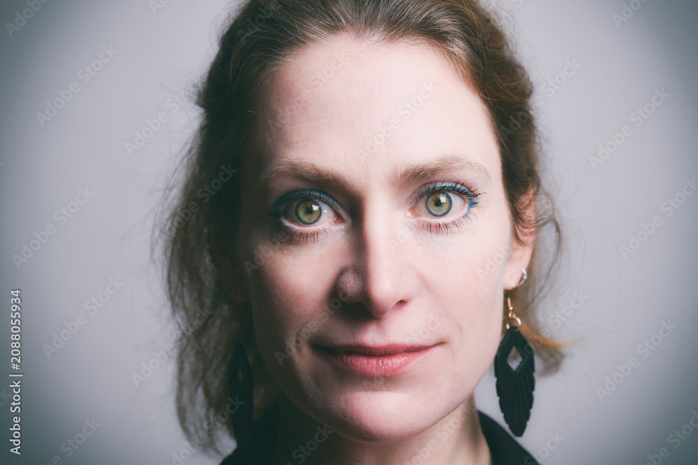 Fototapeta premium Authentisches Porträt einer selbstbewussten Frau mit direktem Blick in die Kamera. Natürliche Schönheit, Emotion, Persönlichkeit, modernes Studioporträt und ausdrucksstarke People-Fotografie.