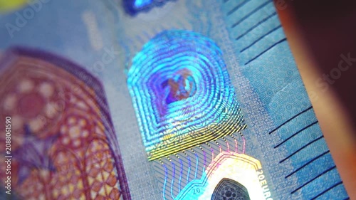 A close-up of the security strip with holographic emblems on the 20-euro banknote. Glowing security holograms on the 20-euro banknote. 4K macro slow motion video at 60 fps.