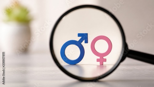 Magnifying glass focusing on male and female symbols highlights concepts of gender equality identity and communication within modern social relationships