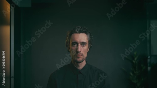 Contemplative man in black shirt seated against dark minimalist background, illuminated with soft diffused light, ideal for business or personal development themes.