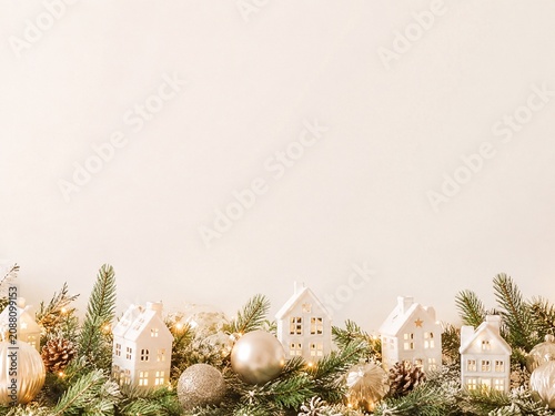Minimal Christmas Village Border Background Soft holiday background with miniature white houses, evergreen branches, ornaments, and warm neutral copy space above