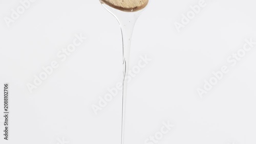 A stream of transparent gel, hyaluronic acid, slowly flows from a wooden spatula, macro.