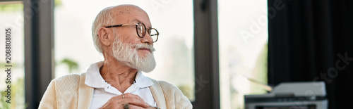Canvas Print A distinguished senior businessman in smart casual attire reflects thoughtfully while working in a modern office