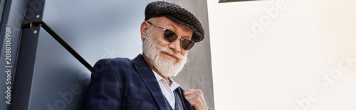 Fotografía A dapper senior gentleman with a grey beard confidently poses outdoors in smart casual attire on a cool autumn day