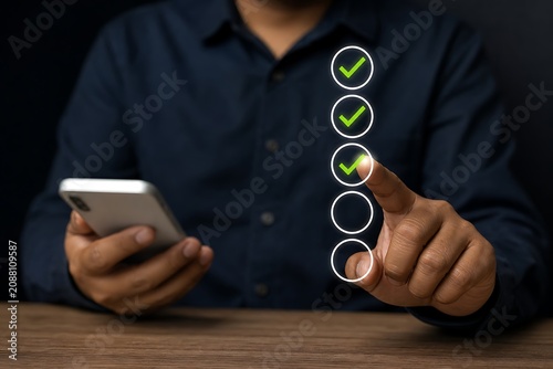Person using smartphone with digital checklist and green checkmarks on wooden table