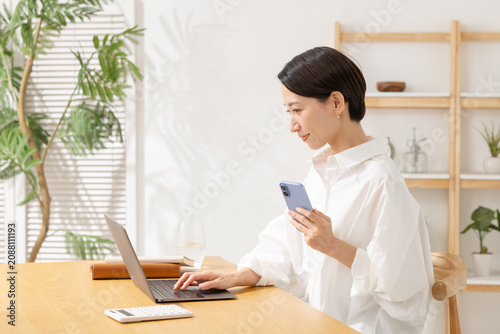 スマホを見ながらパソコン操作する女性
