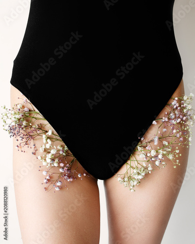 Cropped view of a female body with gypsophila flowers. Creative metaphor for bikini hair removal, laser epilation, waxing, or intimate skincare advertising.
