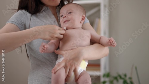 Loving mother cleaning her drooling newborn baby's mouth