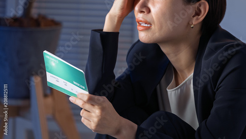 預金通帳を見て悩む女性