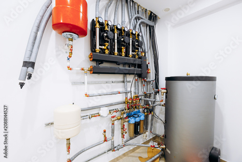 Fotografie Residential boiler room with manifold tank, insulated pipes, valves, gauges, pum