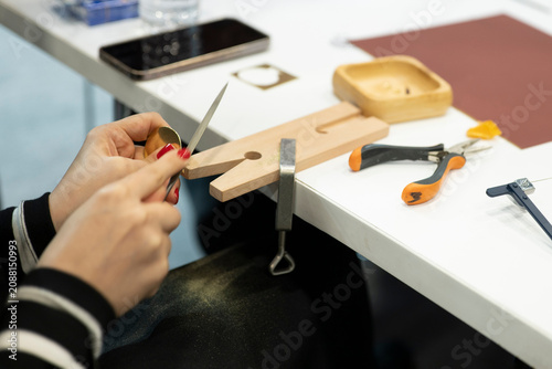 Photography Jewelry artisan filing metal ring on jeweler workbench