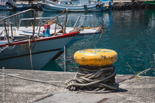 Canvastavla Thick weathered ropes (mooring lines) coiled around yellow bollard for mooring f
