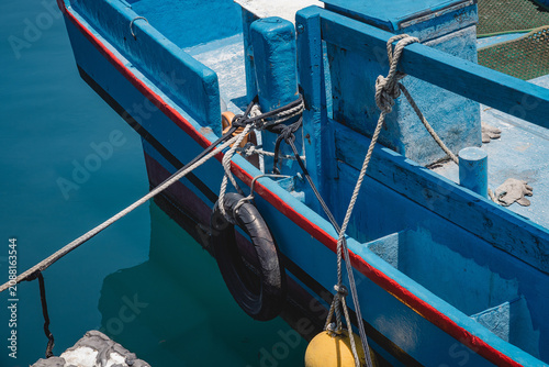 Foto Details of thick weathered ropes tied around mooring bitts on blue fishing boat