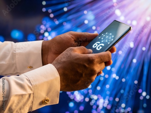 Hands holding smartphone with 6G network technology against fiber optic background