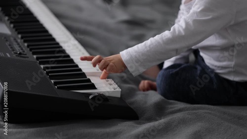 Smiling little child pushes buttons on electric piano. 4k