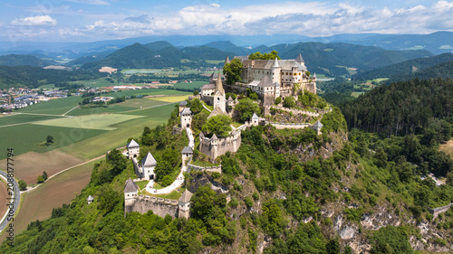 Cinematic drone footage capturing Hochosterwitz Castle on hilltop, fortified walls, dramatic cliffs, summer colors, sweeping aerial movement, historical landmark atmosphere