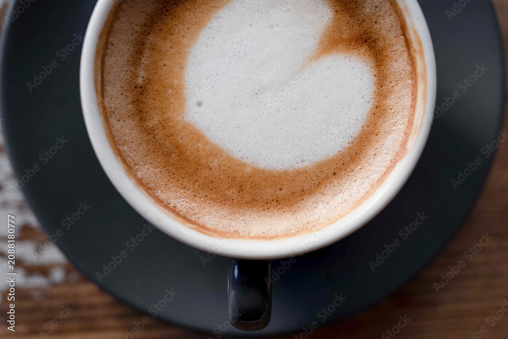 Fototapeta premium Minimalist close-up of a cup of coffee photographed in soft natural light with visible film grain, warm tones and an analog-inspired aesthetic.