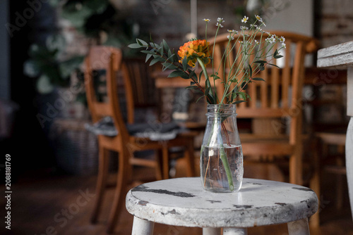 Wildflowers in a glass vase on a rustic white stool