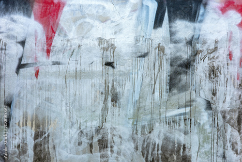 Konstfotografi This urban surface presents a weathered concrete wall heavily layered with expressive, drippy graffiti in shades of silver, black, and red