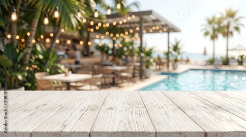 Rustic white wooden tabletop foreground with a blurred tropical resort background featuring a swimming pool, palm trees, and string lights at sunset.