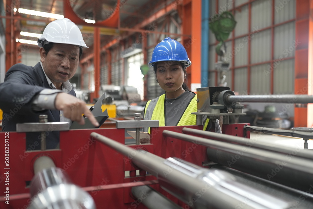 Foto Factory workers discuss project details inside a manufacturing facility while ob