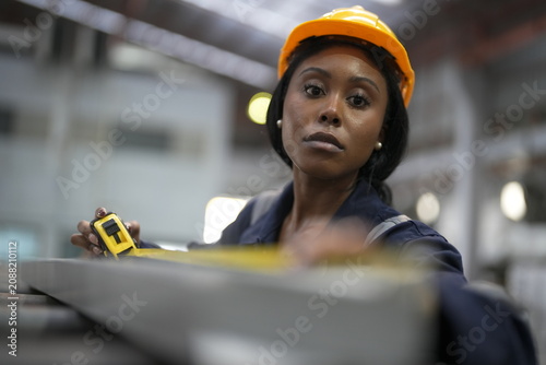 Photography Worker measures metal part in industrial workshop during daytime using tape meas