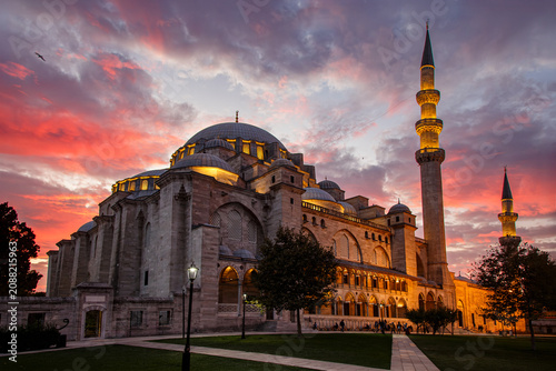 Suleymaniye Mosque illuminated at dramatic pink sunset with glowing minarets in Istanbul, Turkey