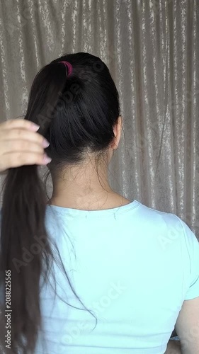 Woman touching brown hair tied in ponytail, healthy hair, hair care and beauty concept.