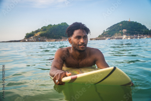 Photography Black man surfing in la concha bay, spain