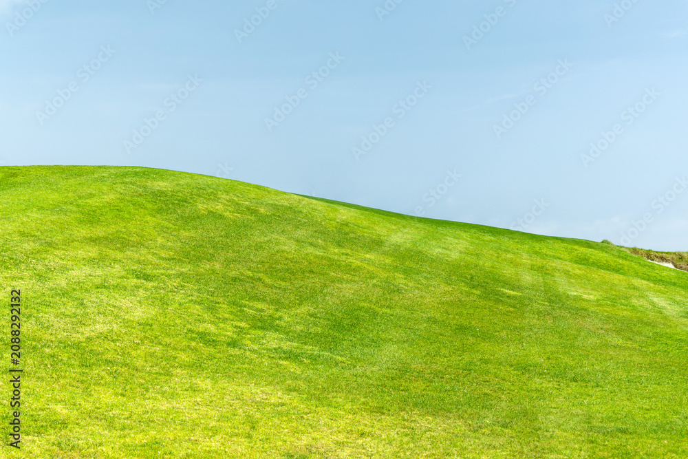 Fototapeta premium Green grass hill under blue sky minimal landscape background