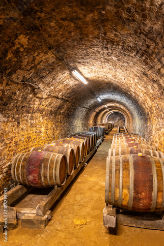 Wine cellar with wooden barrels aging in ancient tunnel